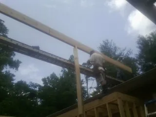 Carpenter setting a ridge beam over a new addition frame — Ice Dam Removal by Roofing Brothers in Mc Clelland