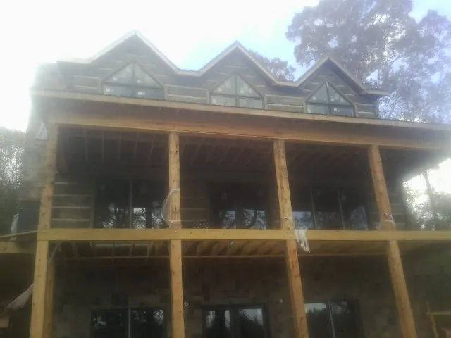 Dormers and porch framing on a large log home under construction — Roof Coating work by our crew in Mc Clelland