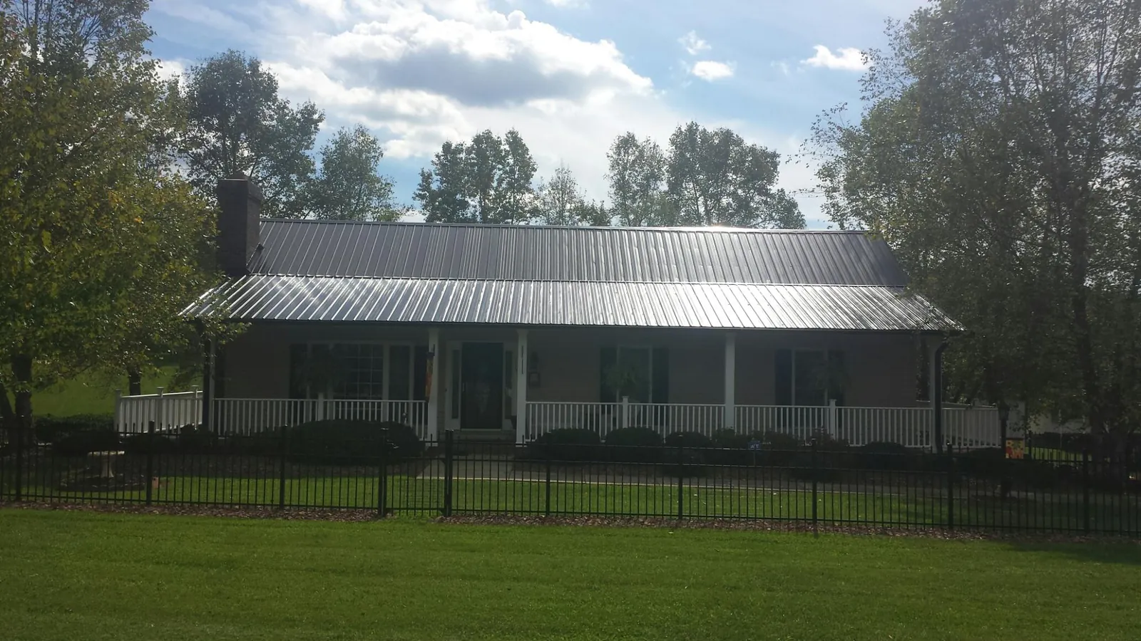 Gray metal roof on a brick ranch with a full width front porch — Gutter Guard Installation work by our crew in Mc Clelland
