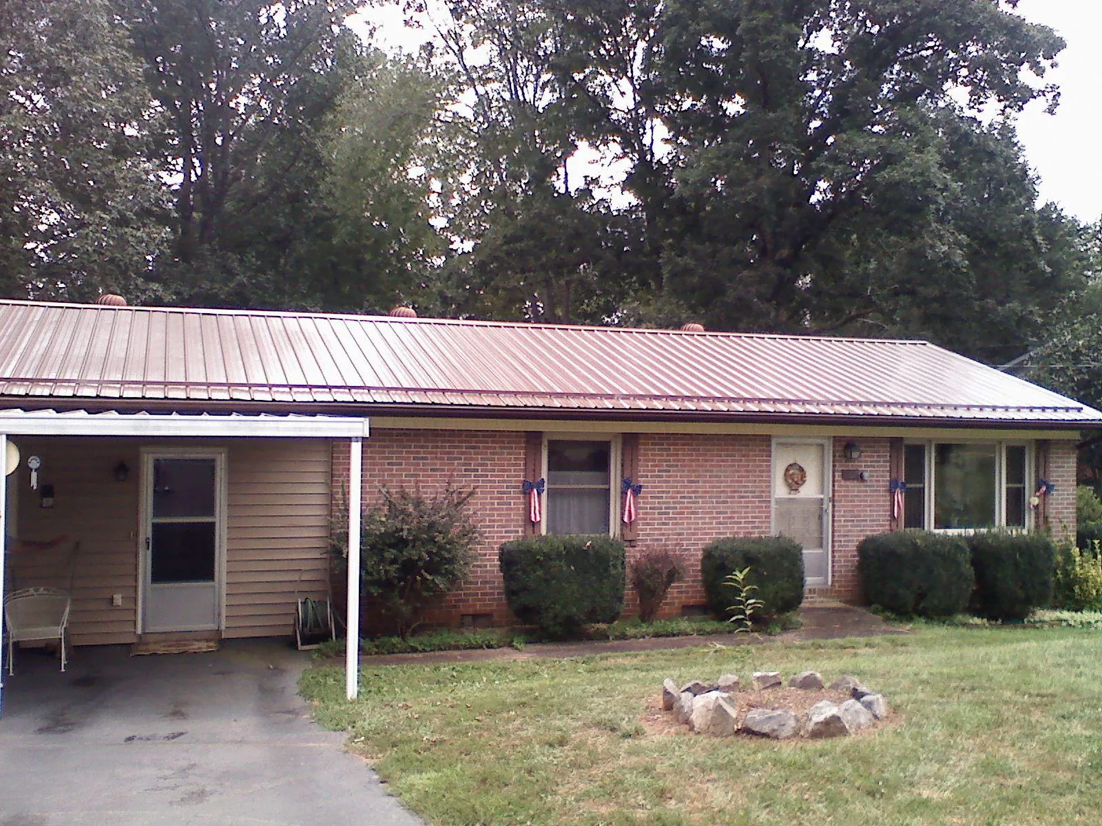Bronze metal roof and carport on a brick ranch home — Roof Repair work by our crew in Mc Clelland
