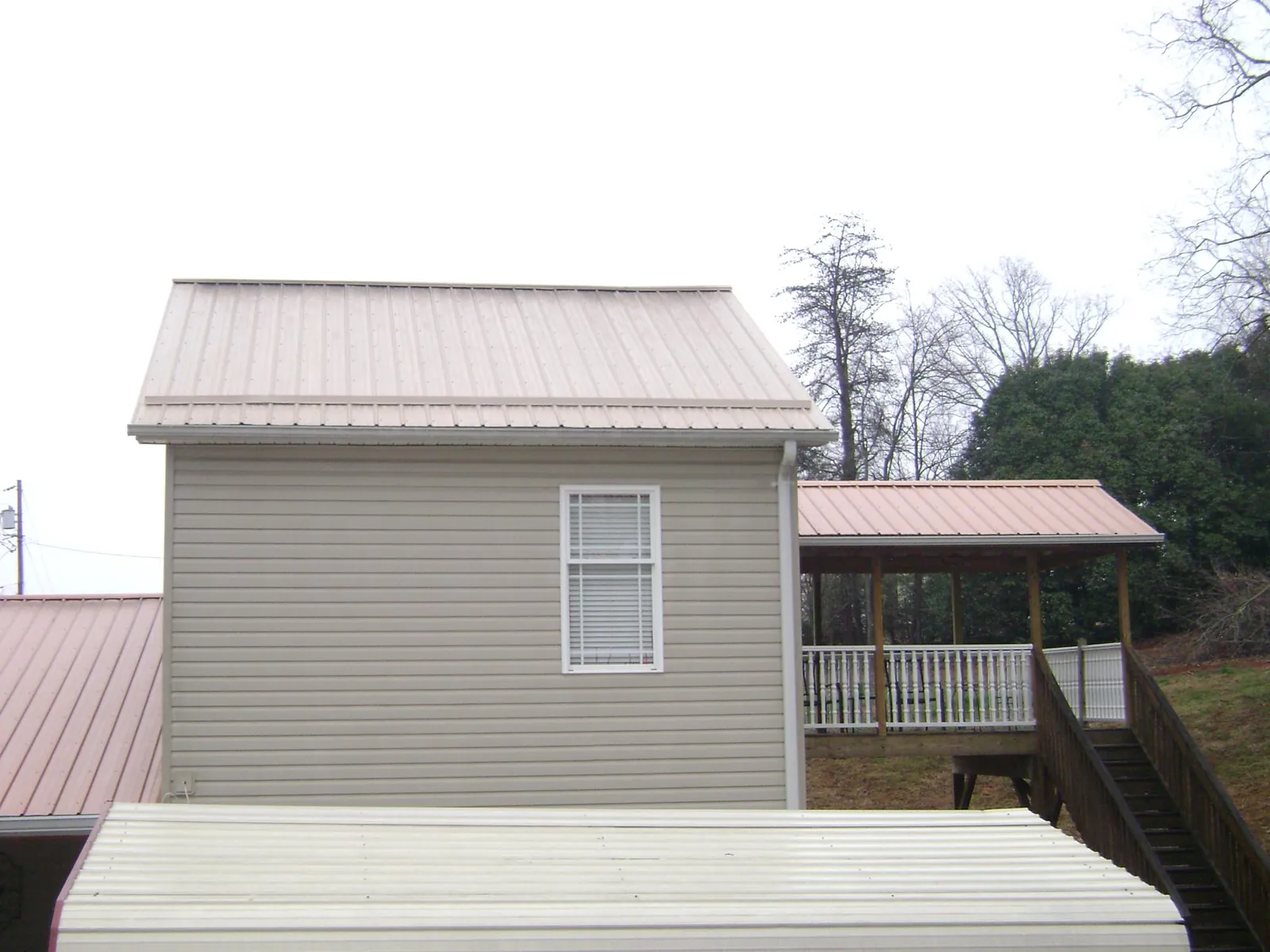 Tan metal roofs on a two story addition and attached porch, from a Roof Replacement job in Mc Clelland