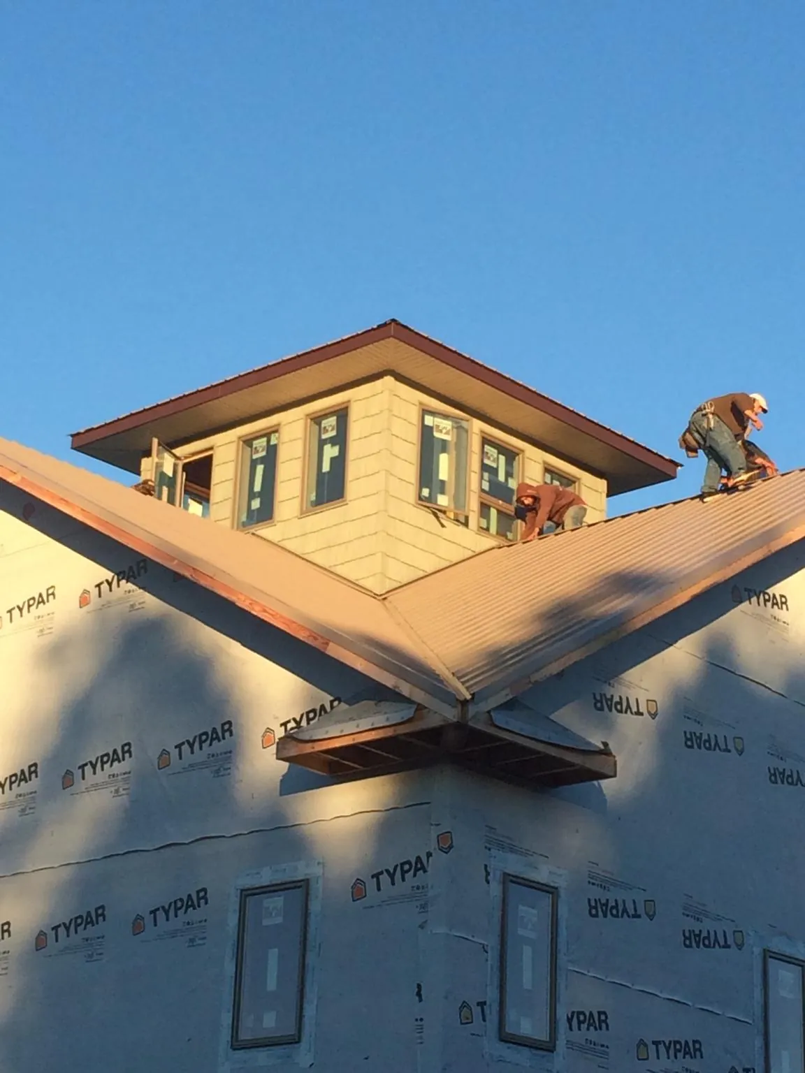 Roofers working around a rooftop cupola on a new metal roof at sunset — Roof Waterproofing in Mc Clelland by Roofing Brothers